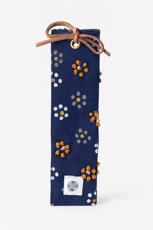 Navy blue bookmark with floral pattern and brown drawstring on a navy background